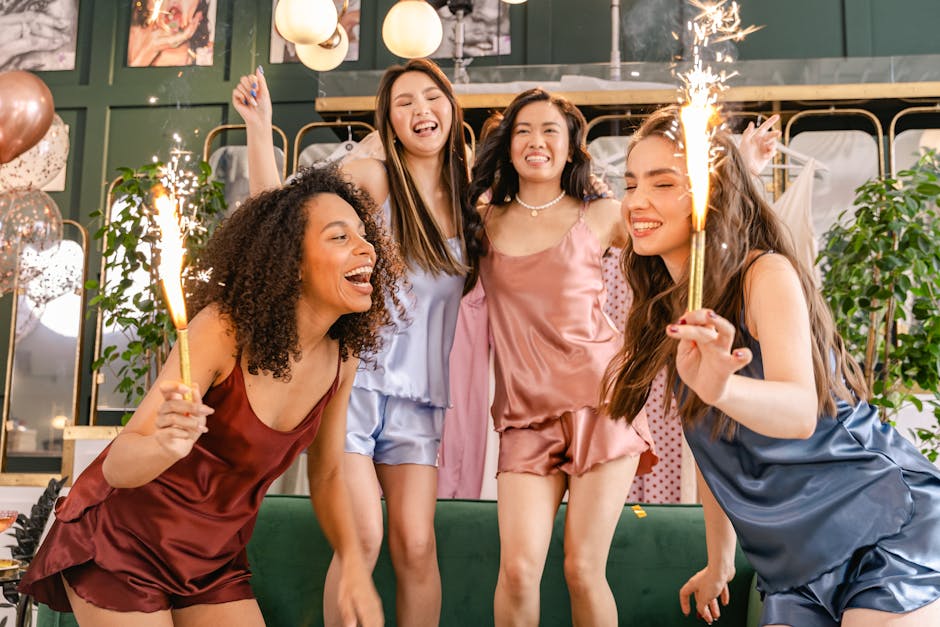 Group of young women celebrating indoors with sparklers, wearing colorful sleepwear, enjoying a joyful moment.